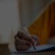 Close-up of a person writing in a notebook with a pen.