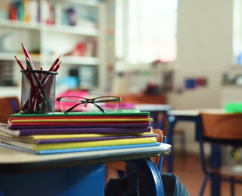 Student desk with pencil and standardized test booklet in soft natural light, empty classroom setting.